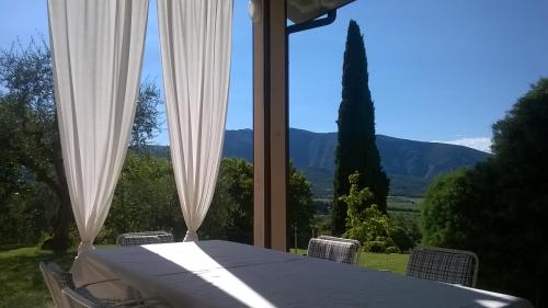 a table with white curtains and a view of mountains at Carmen de Nella Eco Lodge 4* in Caprino Veronese