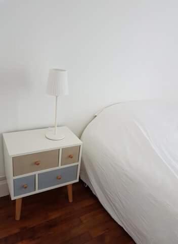 - une chambre avec un lit et une table de chevet avec une lampe dans l'établissement Apt spacieux proche Lyon Guillotte, à Villeurbanne