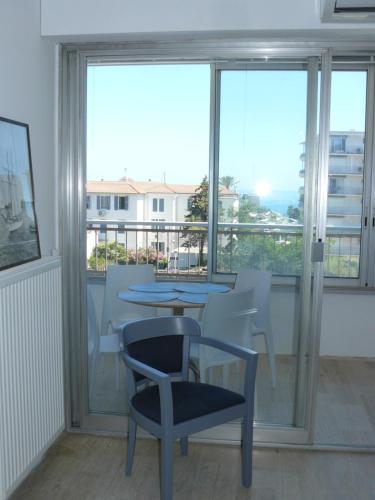 une table et une chaise dans une chambre avec fenêtres dans l'établissement Natalilocs, au Golfe-Juan
