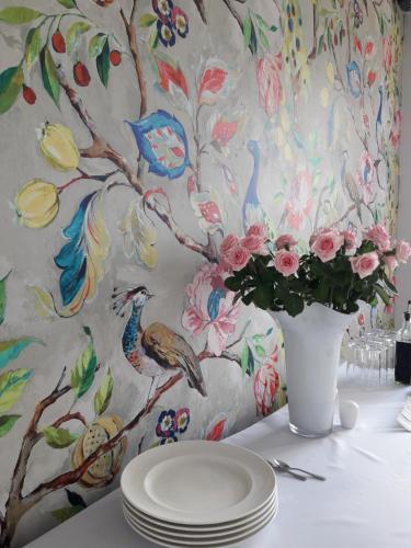 a table with plates and a vase with flowers at Apartamenty M&M in Mikołajki