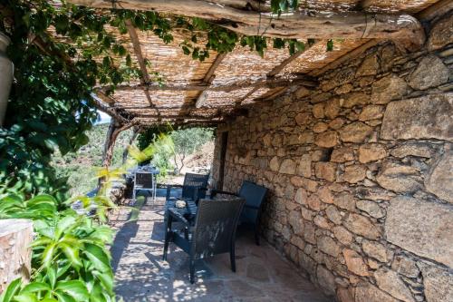 a stone walled patio with a table and chairs at Les Bergeries "Le figuier" in Omessa