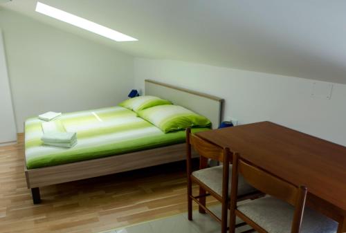 una camera da letto con un letto con cuscini verdi e un tavolo di Apartments & Room Toni a Valun