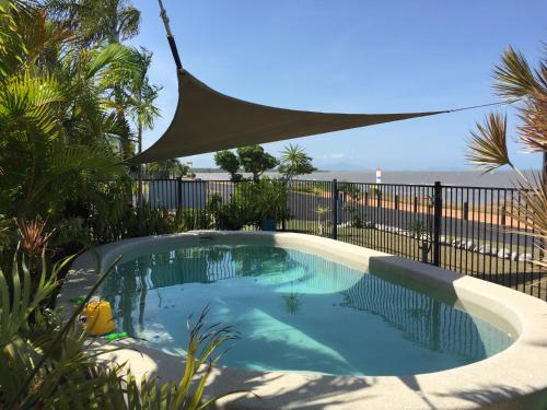a swimming pool with a large umbrella on top of it at Cardwell Beachfront Motel in Cardwell