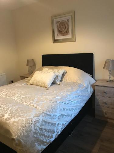 een bed met witte lakens en kussens erop bij River Ness Apartments in Inverness