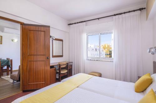 Una habitación de hotel con una cama y una ventana. en Rosamar Apartamentos, en Armação de Pêra