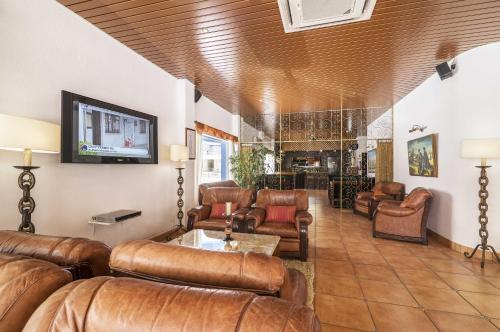a living room with leather furniture and a flat screen tv at Rosamar Apartamentos in Armação de Pêra