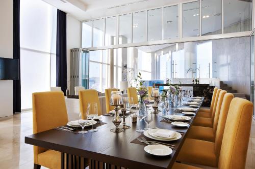 a dining room with a long table and yellow chairs at Hotel Entra Gangnam in Seoul