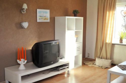 sala de estar con TV en un soporte blanco en Ferienwohnung-Kuechler en Oelsnitz