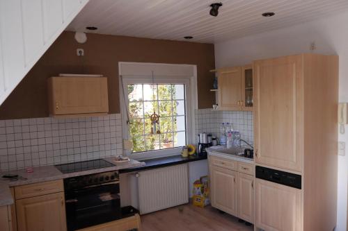 une cuisine avec des placards en bois et une fenêtre dans l'établissement Ferienwohnung-Kuechler, à Oelsnitz