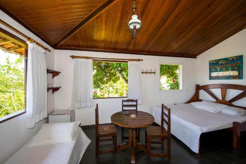 a bedroom with two beds and a table and chairs at Pousada Natureza in Morro de São Paulo