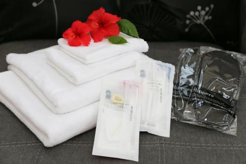 a pile of towels with a red flower on top at Palm Villa Ishigakijima igusa in Ishigaki Island