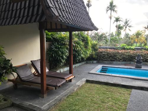 an umbrella and chairs next to a swimming pool at Bali Breeze Bungalows in Ubud