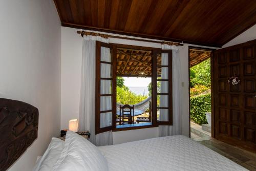 a bedroom with a bed and a large window at Pousada Natureza in Morro de São Paulo