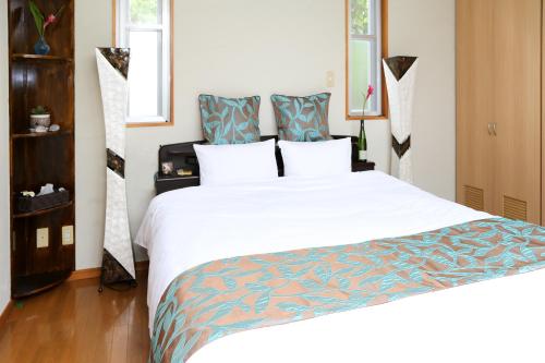 Un dormitorio con una gran cama blanca con toques azules en Palm Villa Ishigakijima igusa, en Ishigaki Island