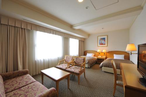 a hotel room with two beds and a couch at HOTEL MYSTAYS Matsuyama in Matsuyama