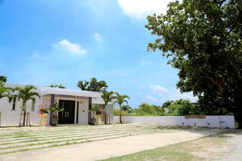 a white building with a tree in front of it at Palm Villa Ishigakijima igusa in Ishigaki Island