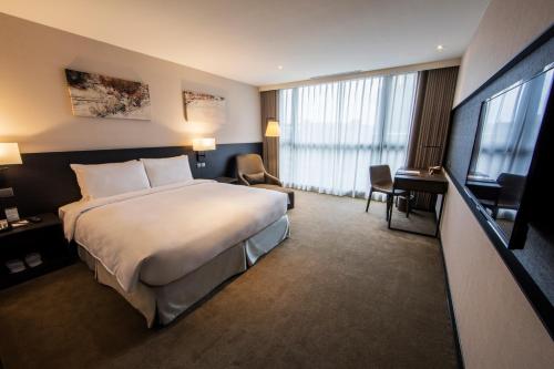 a hotel room with a large bed and a desk at Platinum Hotel in Xindian