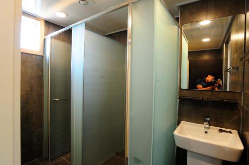 a bathroom with a shower and a sink and a mirror at Hannah Guesthouse in Jeju