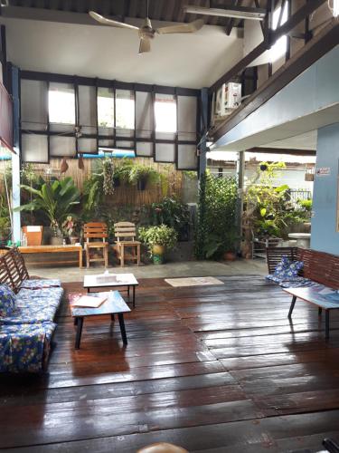 una sala de estar con sofás, mesas y plantas. en Canaan Guesthouse, en Kanchanaburi