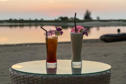two cocktails sitting on a table with flowers in them at Angkana Bungalows adults only in Thong Sala