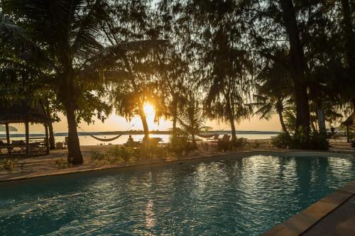 a swimming pool in front of a beach with the sunset at Angkana Bungalows adults only in Thongsala