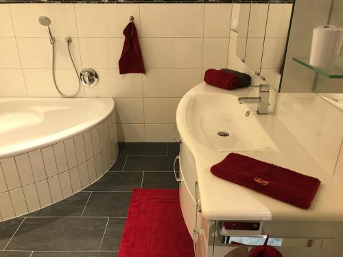 ein Badezimmer mit einem Waschbecken, einer Badewanne und einem Spiegel in der Unterkunft Appartement Elisabeth in Umhausen