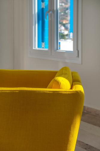 a yellow couch in a room with a window at Syros Private House with superb sea view in Kinion