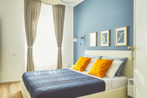 een blauwe slaapkamer met een bed met oranje kussens bij Casa Anne Marie in La Spezia