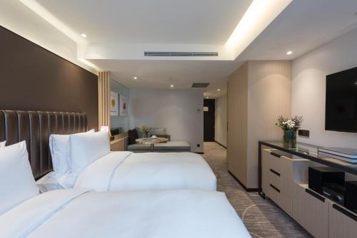 a hotel room with two beds and a flat screen tv at K Hotel Taipei Chang-An in Taipei