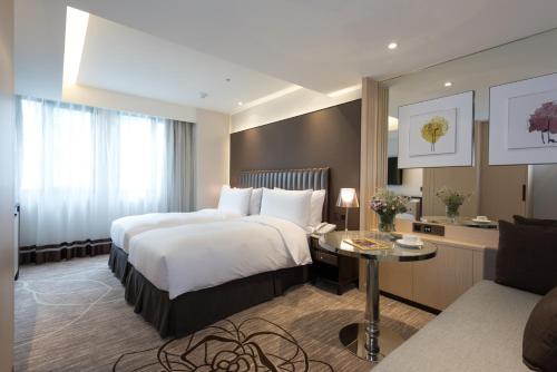 a hotel room with two beds and a table at K Hotel Taipei Chang-An in Taipei