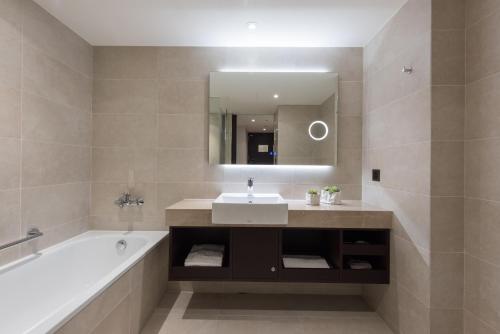 a bathroom with a sink and a tub and a mirror at K Hotel Taipei Chang-An in Taipei