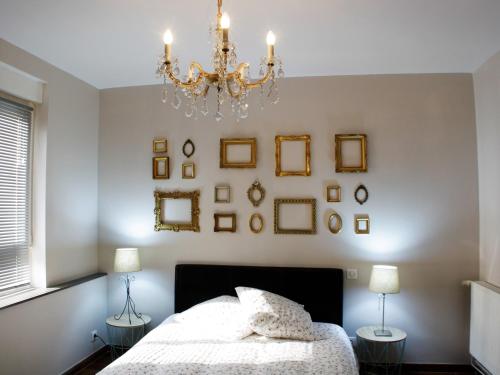 a bedroom with a chandelier and pictures on the wall at L'ARBOGAST in Herrlisheim