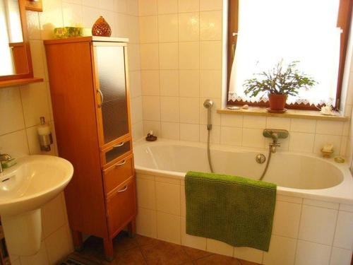 a bathroom with a bath tub and a sink at Ferienwohnung-BergIdylle-bei-Hotel-BERGHOF in Lichtenhain