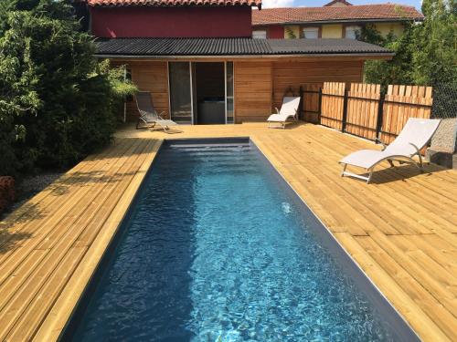 a swimming pool on a wooden deck with two chairs at O Lodge in Cleppé