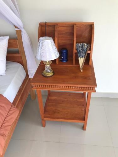 a night stand with a lamp on a table next to a bed at GumiBali Villa in Tirtagangga