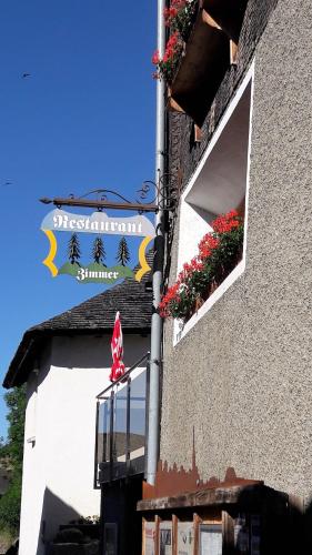 a sign on the side of a building with flowers at Hotel-Restaurant Drei Tannen in Niederwald