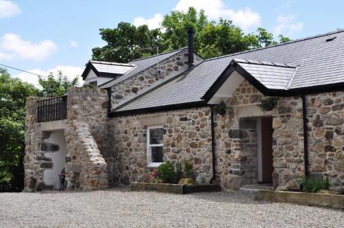 an old stone house with a garage at The Barn at Cae Bach in Gwalchmai