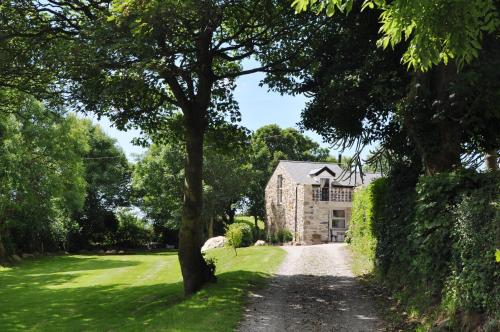 a dirt road leading to a large stone house at The Barn at Cae Bach in Gwalchmai