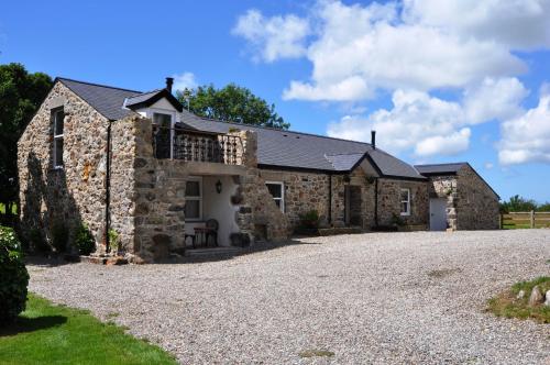 an old stone house with a gravel driveway at The Barn at Cae Bach in Gwalchmai