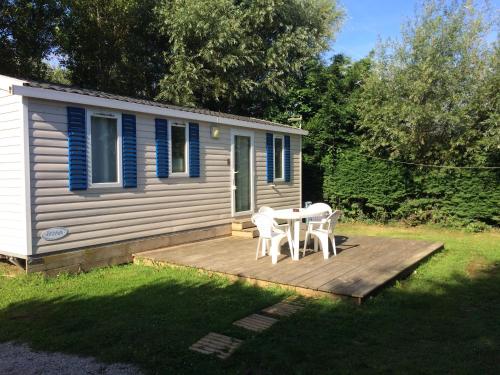 a small cabin with a table and chairs on a deck at Camping De Collignon in Cherbourg en Cotentin