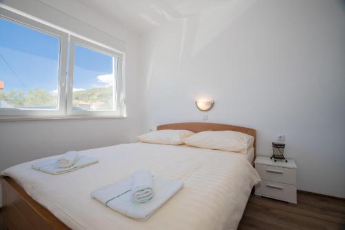 a bedroom with a large white bed with towels on it at Apartments PETRUSIC in Rab
