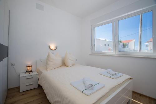 a bedroom with a white bed with two towels on it at Apartments PETRUSIC in Rab