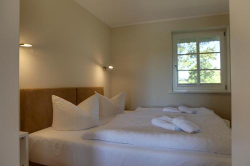 Un dormitorio con una cama blanca con almohadas y una ventana en Haus Sonnenblume, en Lohme