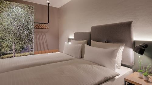 a bedroom with a bed with white pillows and a window at Hotel the YARD Berlin in Berlin