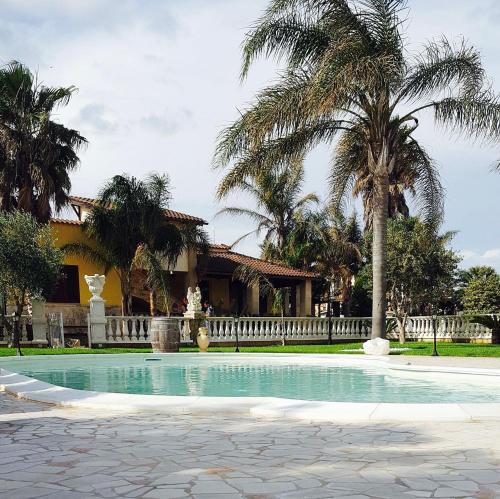 a swimming pool in front of a house with palm trees at La Pajara in Nardò