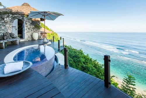 a deck with a swimming pool next to the ocean at Ungasan Beach Villas in Uluwatu