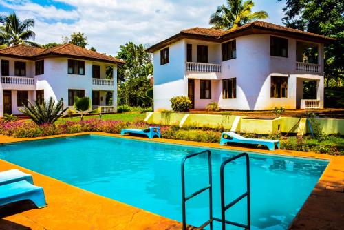 a villa with a swimming pool in front of a house at Keys Hotel Mbokomu Branch in Moshi