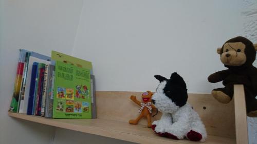 dos animales de peluche sentados en un estante con libros en Stella Maris Hosting en Haifa