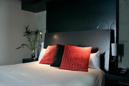 a bedroom with a white bed with red pillows at Grand Times Hotel in Quebec City