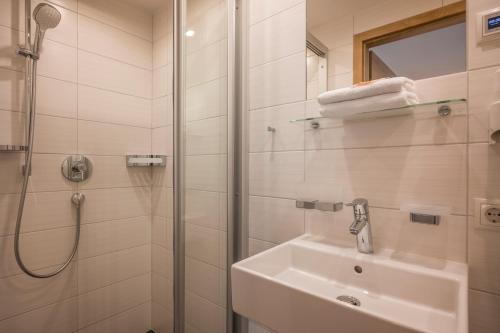 a white bathroom with a shower and a sink at Garni Nill in Schwendau